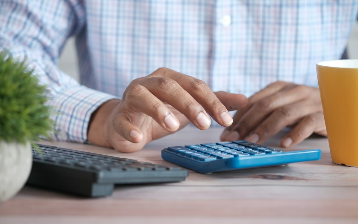 Person working on a calculator next to a keyboard