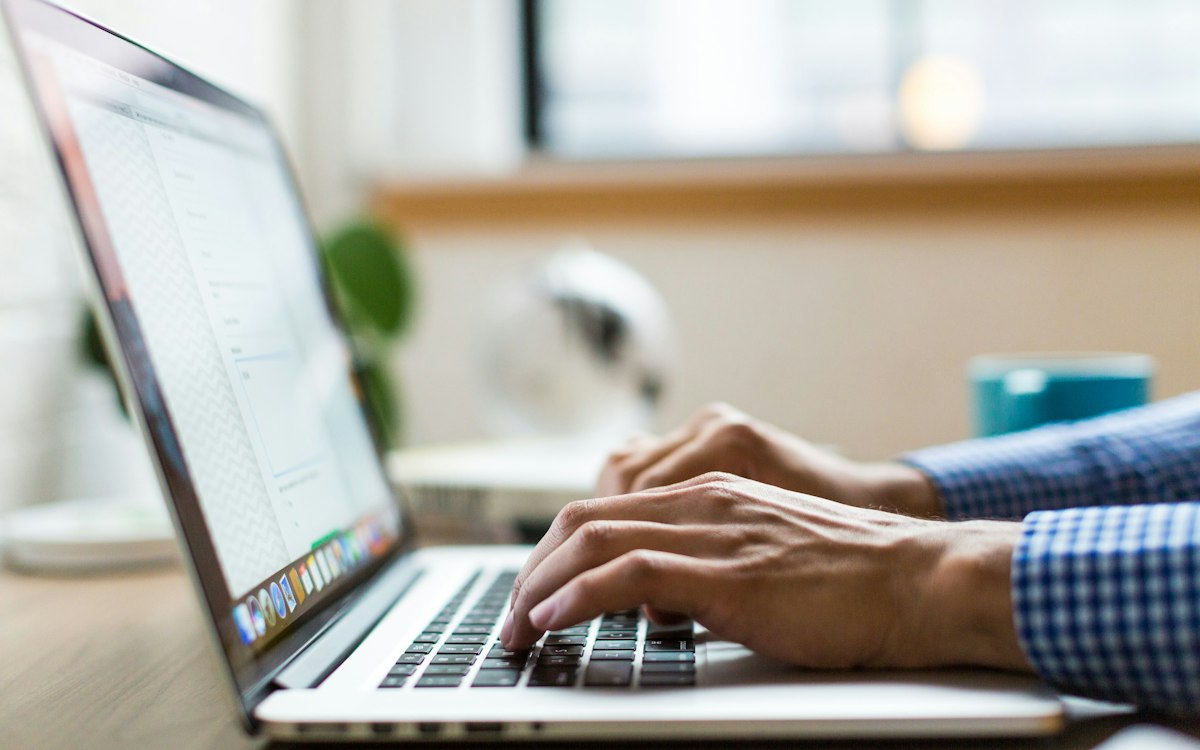 Hands typing on a laptop keyboard at a desk
