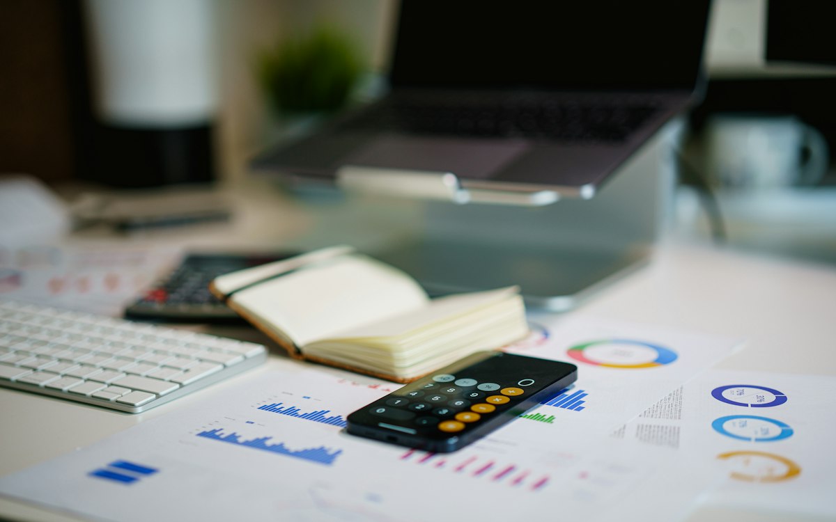 Desk with printed charts, a calculator and a notebook