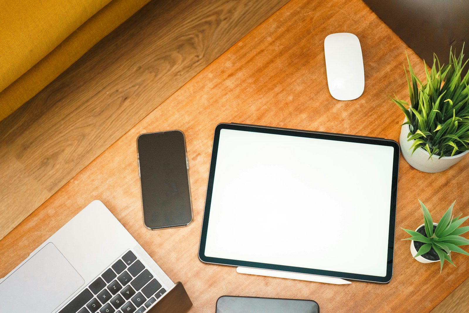 A laptop, tablet and phone laid out on a desk