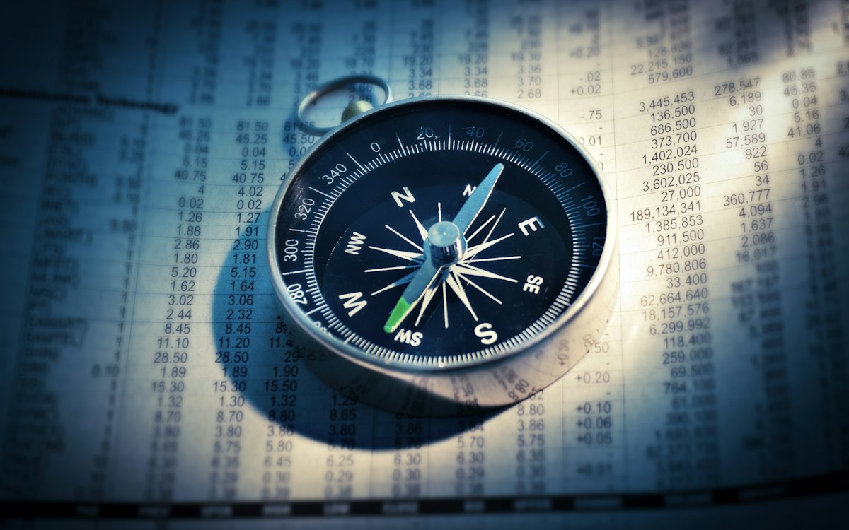 Compass lying on printed financial tables