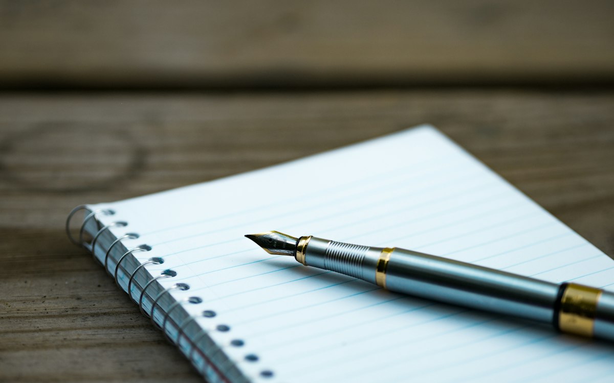 Fountain pen resting on an open spiral notebook