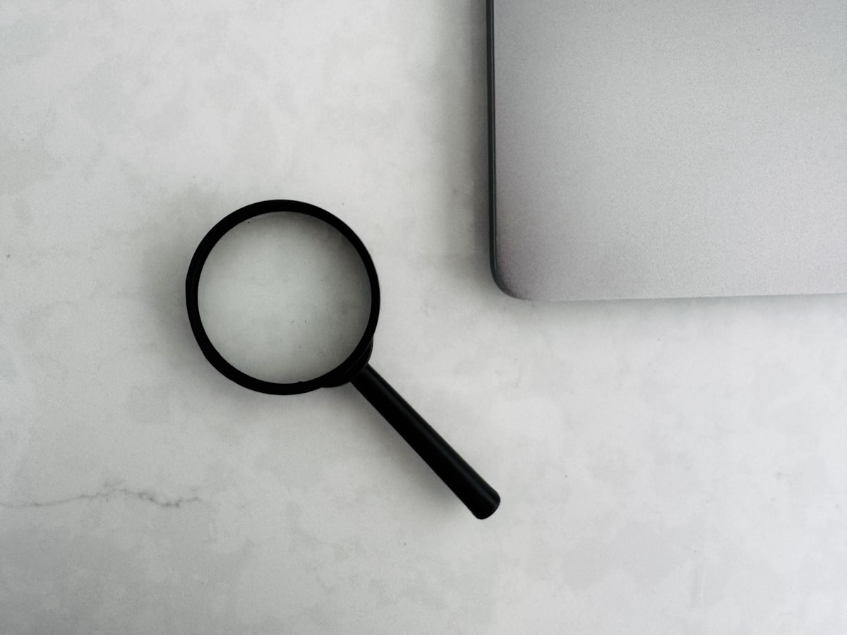Magnifying glass beside a laptop on a desk