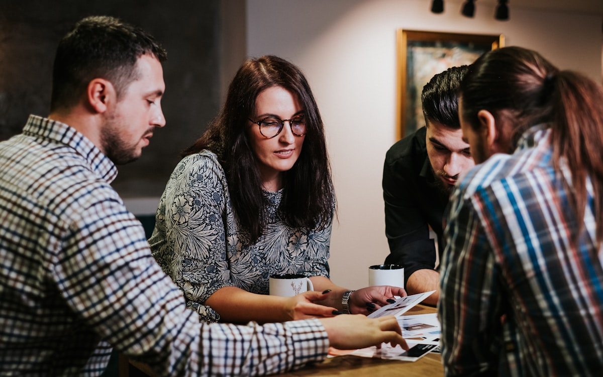Four people reviewing documents around a wooden table