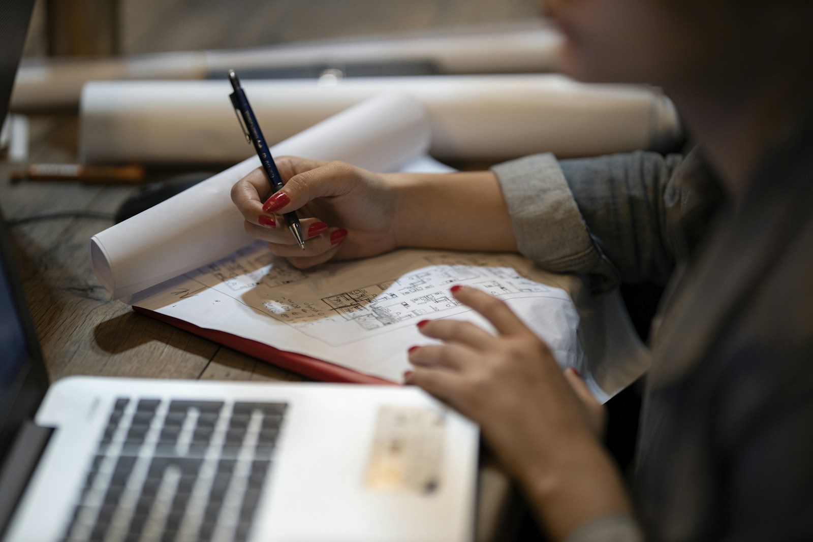 A person writing notes by hand next to a laptop